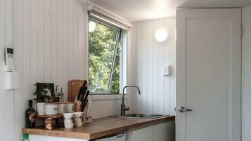 A compact kitchen with a window, a sink, and a refrigerator.