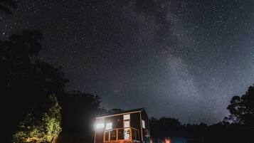 A house with a large window, a porch, and a starry night sky.