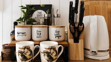 Un comptoir de cuisine avec des tasses à café, une machine à café et un ensemble de couteaux.