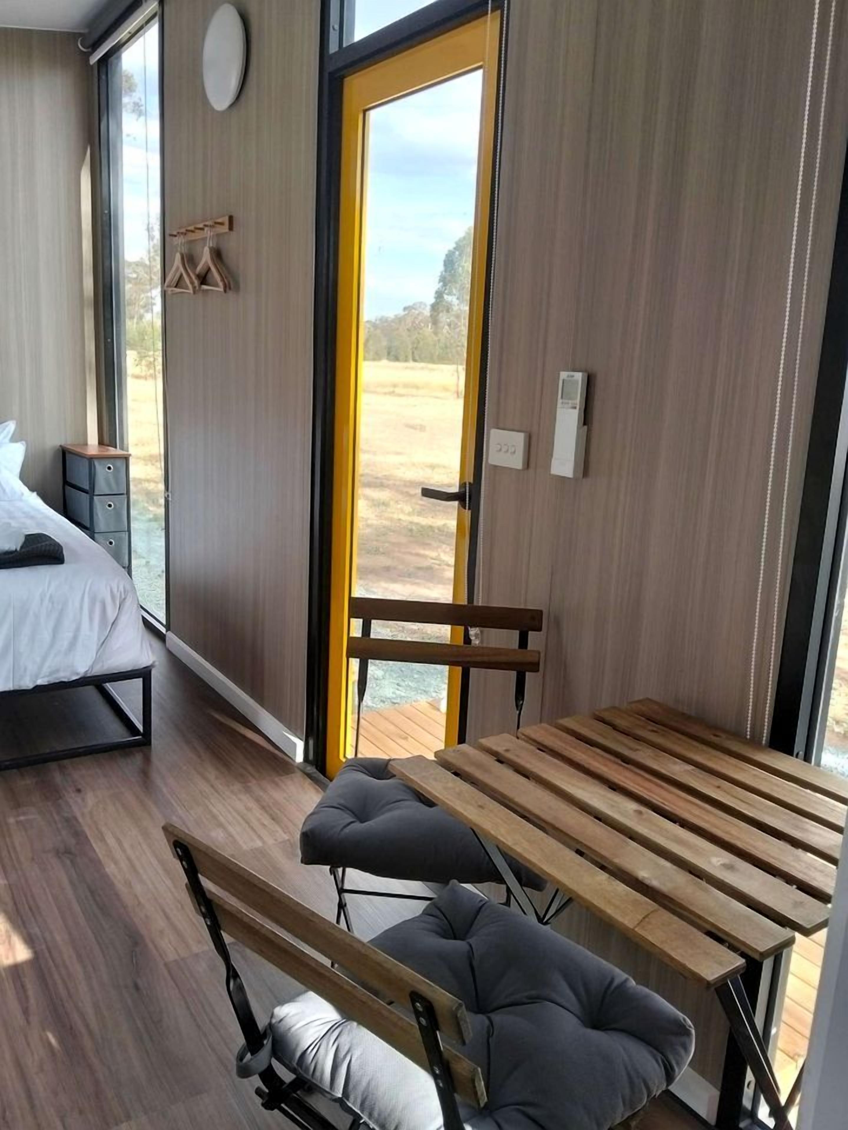 Quarto moderno com uma cama, um banco e uma mesa. Há uma janela com vista para o exterior.