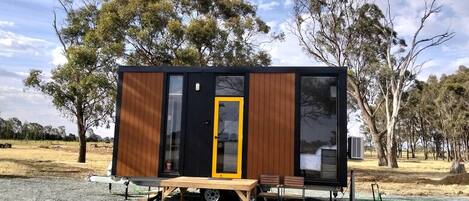 A small, single-story cabin with a sliding door, a table, and two chairs outside.