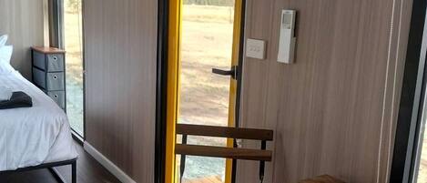 Ein modernes Zimmer mit Bett, Sitzbank und Tisch. Ein Fenster bietet Blick ins Freie.