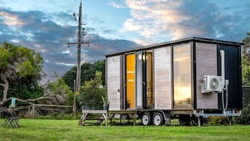 A mobile home with a sliding door, a small porch, and a portable air conditioning unit.