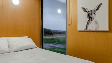 Une chambre à coucher avec un lit, une fenêtre donnant sur un paysage et un tableau représentant un kangourou accroché au mur.