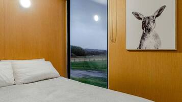 Een slaapkamer met een bed, een raam met uitzicht op een landschap en een schilderij van een kangoeroe aan de muur.