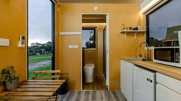 Une cuisine compacte équipée d’un four à micro-ondes, d’un évier et d’un plan de travail en bois.