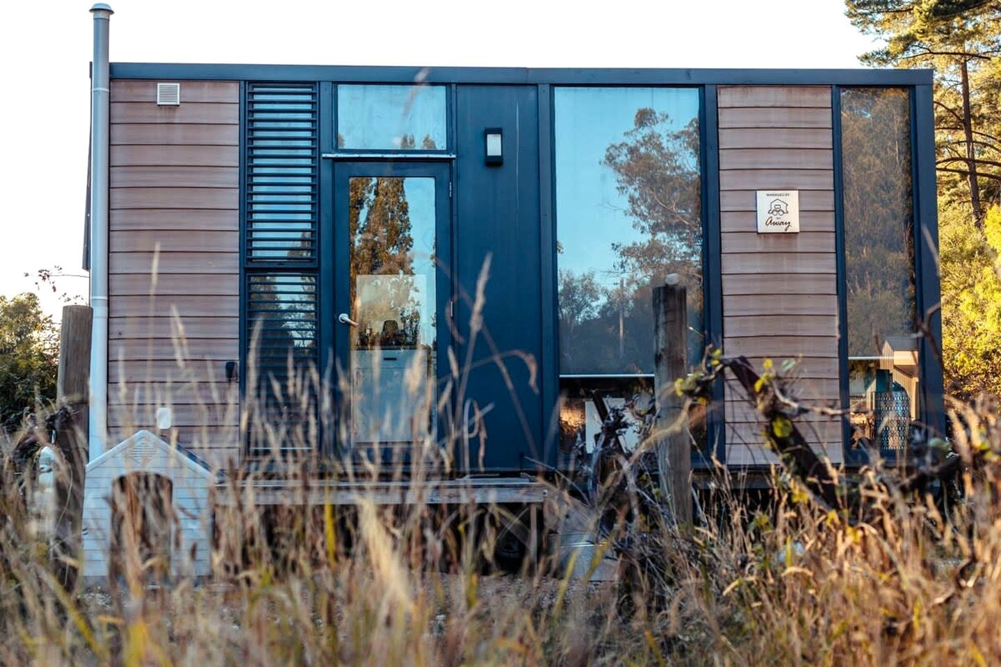 A modern, single-story building with a dark blue exterior, large windows, and a visible door.