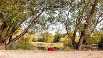 A natural landscape with a body of water, trees, and a red object on the ground.