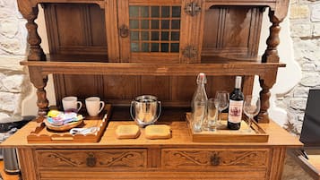 Una zona de bar con madera, una bandeja de aperitivos, una botella de vino y copas.