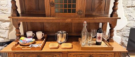 A wooden bar area with a tray of snacks, a bottle of wine, and glasses.