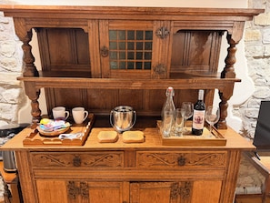A wooden bar area with a tray of snacks, a bottle of wine, and glasses.