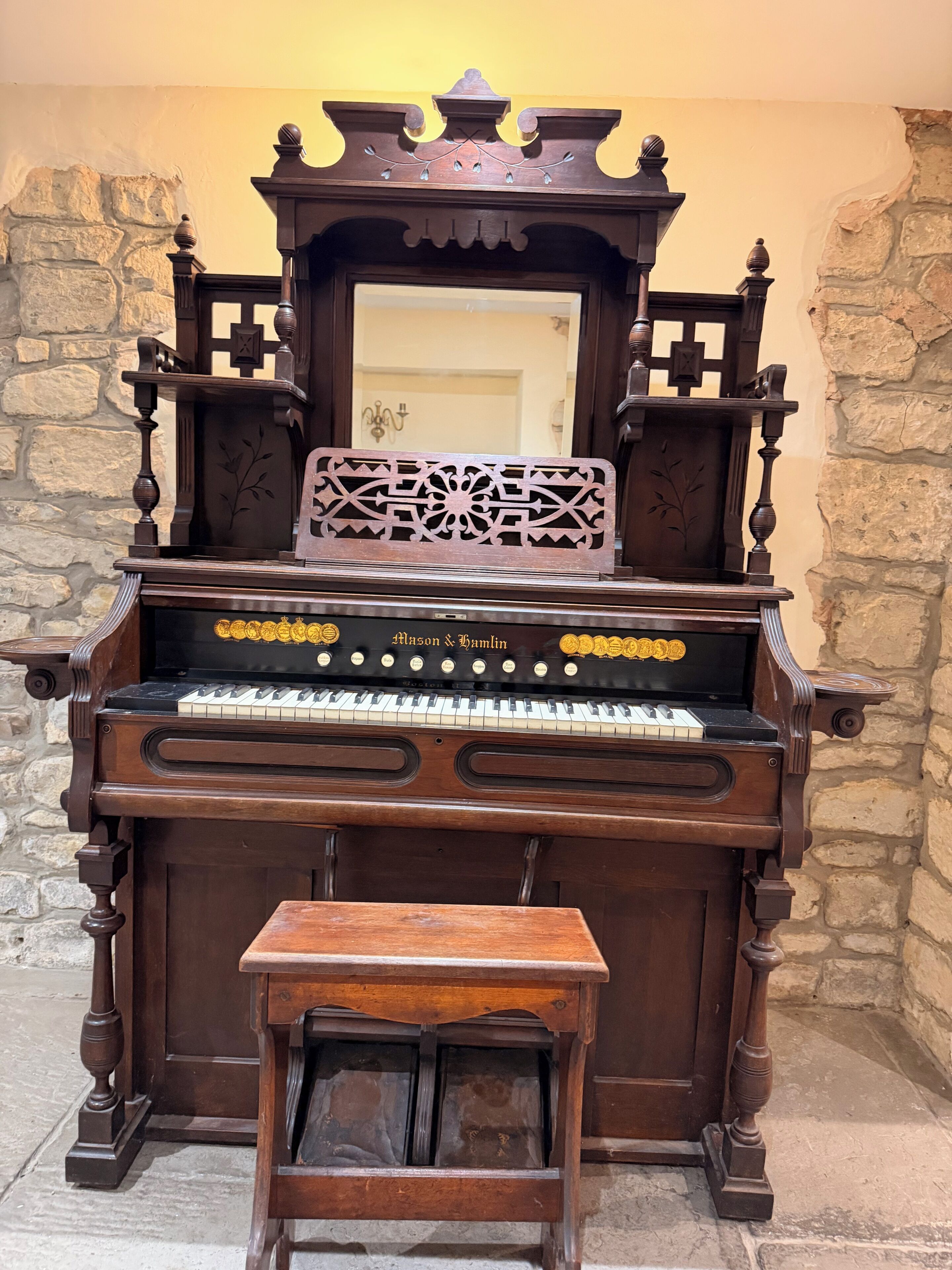 A grand piano with intricate carvings and a decorative mirror above it.