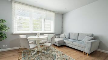 Uma sala de estar moderna com um sofá cinzento, uma mesa redonda branca e um tapete estampado.