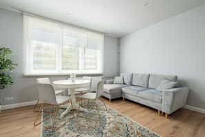 Ein stilvolles Wohnzimmer mit grauem Sofa, einem runden weißen Tisch und einem gemusterten Teppich.