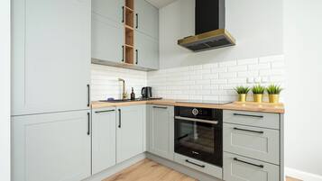 Uma cozinha moderna com armários brancos, um forno Bosch e bancada de madeira.