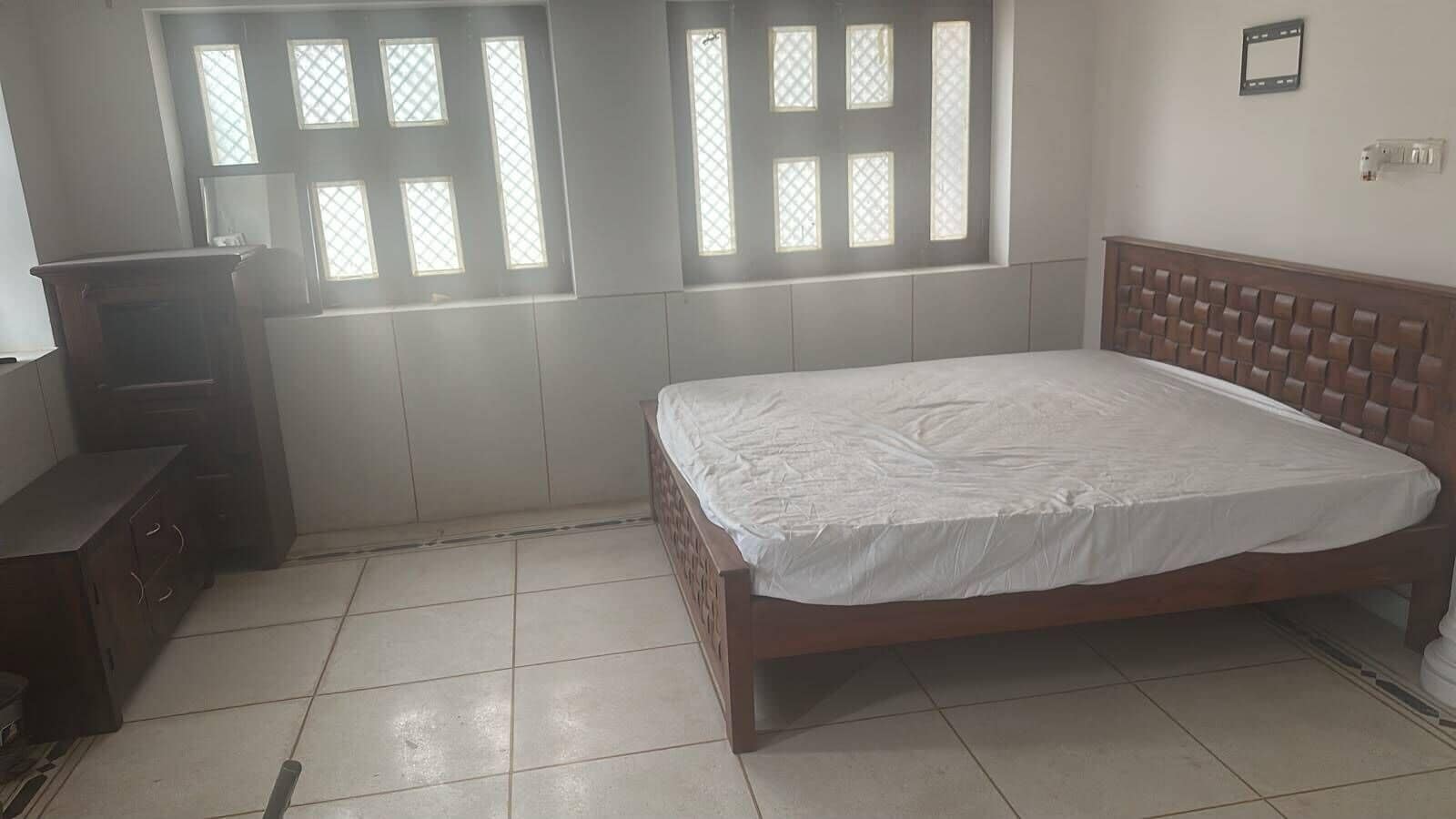 Une chambre à coucher avec un lit, une commode et une fenêtre équipée de stores.