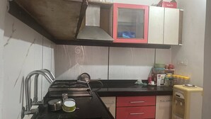 Una cocina compacta con estufa a gas, un lavamanos y un refrigerador pequeño.