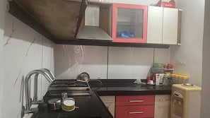 A compact kitchen with a gas stove, a sink, and a small refrigerator. - 18 Mohanpura (Jodhpur)