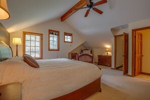 A bedroom with a large bed, a ceiling fan, and a sloped ceiling. - Peak and Pond Mountain View Retreat hot tub theater sauna. (Killington)