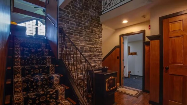 A staircase with a patterned carpet leading to a room with a fireplace and a door to another room. - Peak and Pond Mountain View Retreat hot tub theater sauna. (Killington)