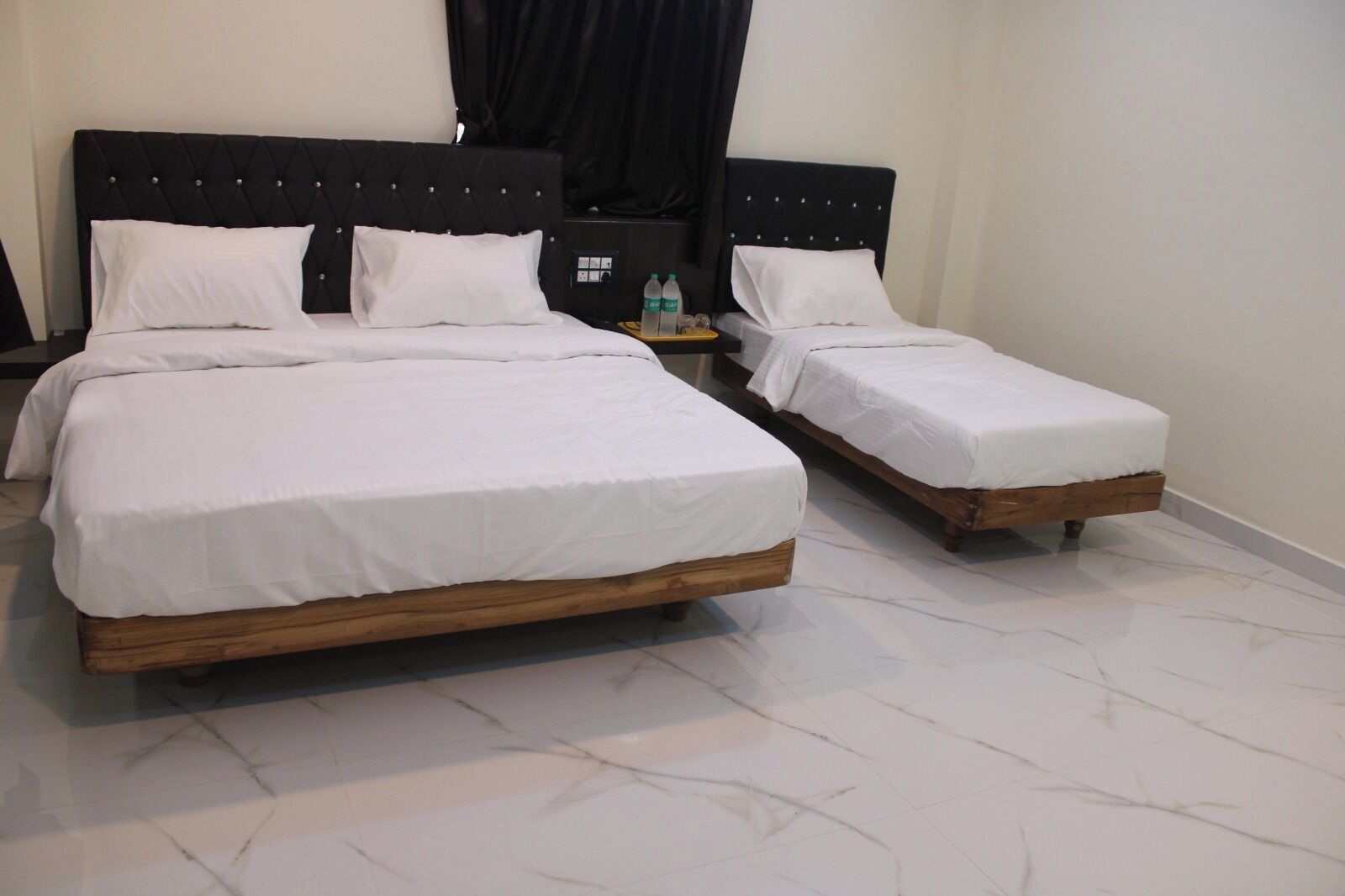 Een hotelkamer met twee bedden, een nachtkastje en een waterfles.