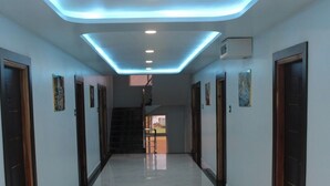 A hallway with a reflective floor, recessed lighting, and doors on both sides.