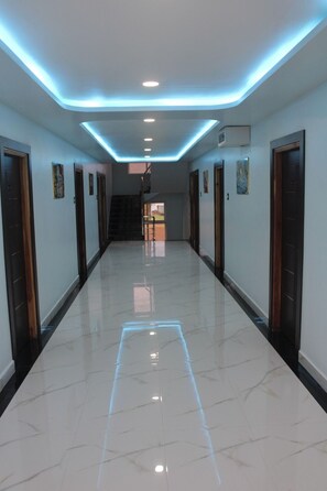 A hallway with a reflective floor, recessed lighting, and doors on both sides.