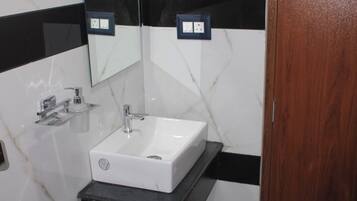 Ein Badezimmer mit einem weißen Waschbecken, einer schwarzen Arbeitsplatte und einer Holztür.