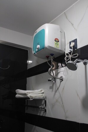 A bathroom with a wall-mounted hand dryer, a towel rack with folded towels, and a showerhead.