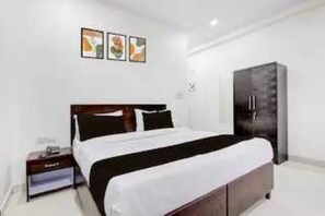 A hotel room with a bed, a wardrobe, and a nightstand. - Classic Green Residency (New Delhi)