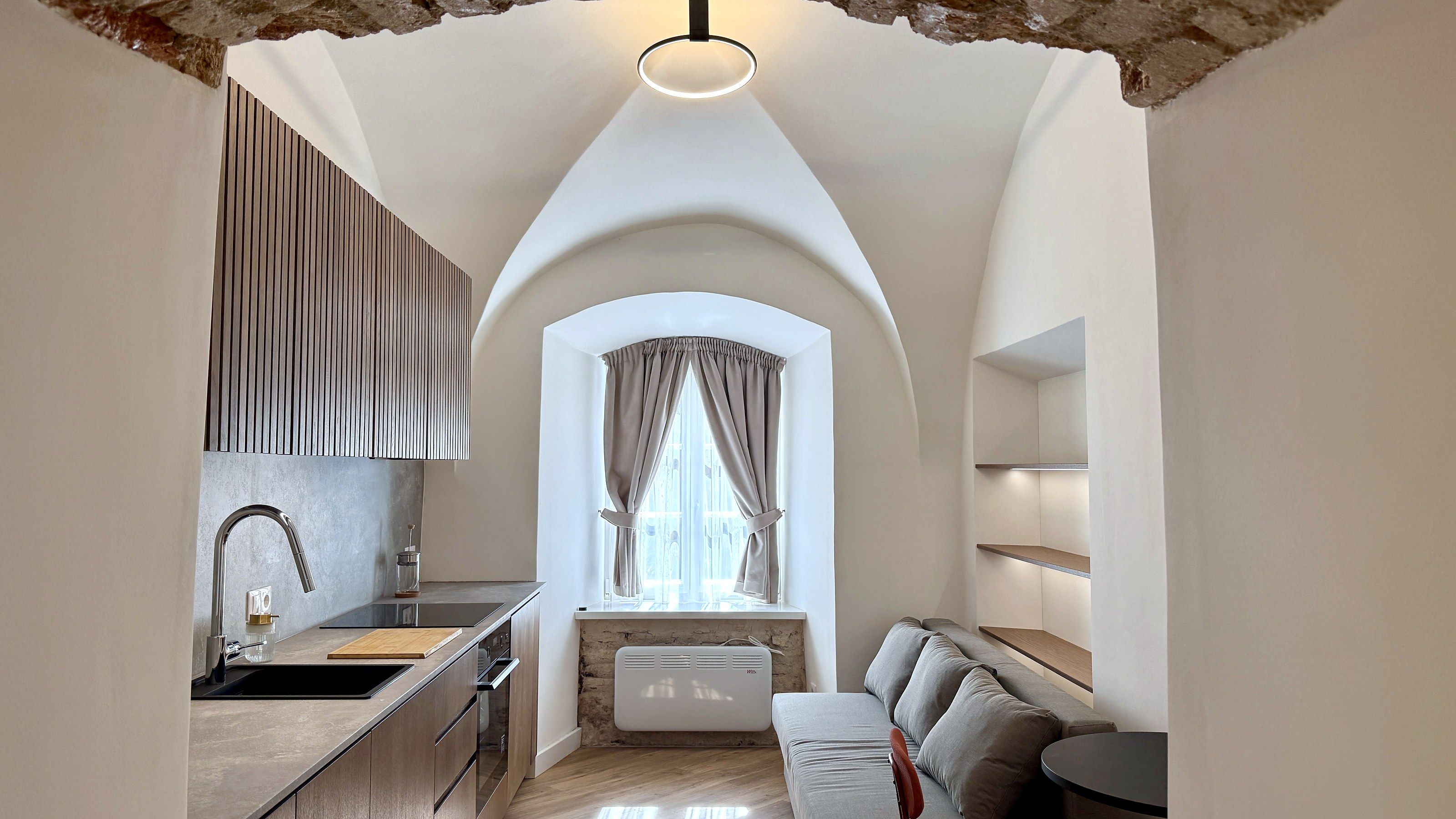 A modern kitchen with a built-in oven, a sink, and a window with curtains.