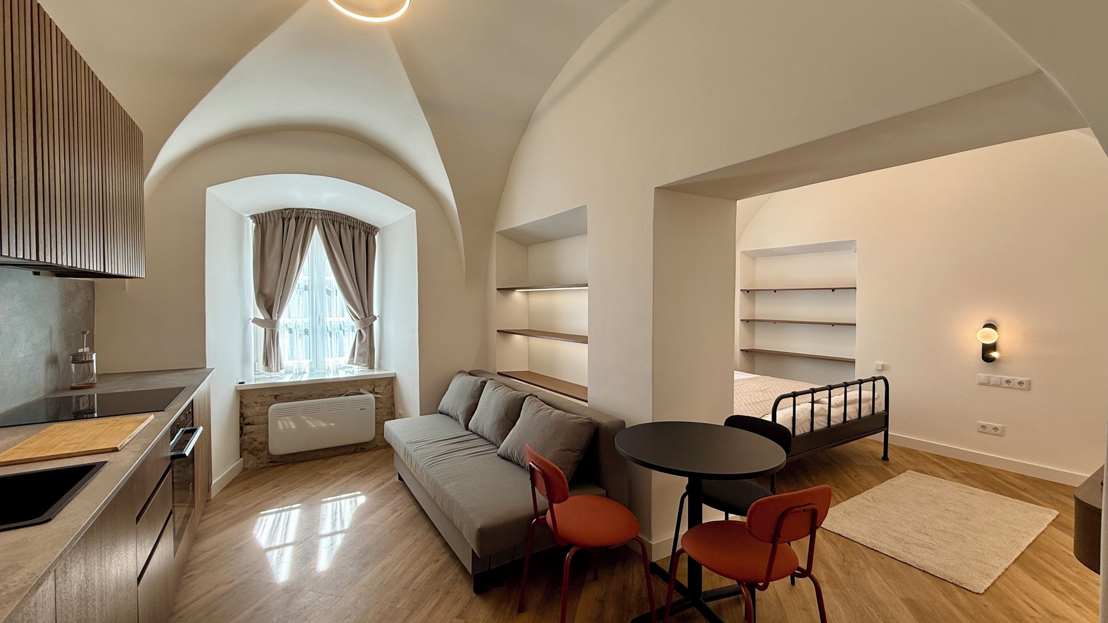 A modern apartment with a kitchen, dining area, and a cozy living space with a sofa and chairs.