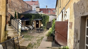 A narrow alley with a café, outdoor seating, and a staircase leading to a building.