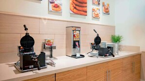 A self-service breakfast station with waffle makers and syrup dispensers.