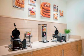 A self-service breakfast station with waffle makers and syrup dispensers.