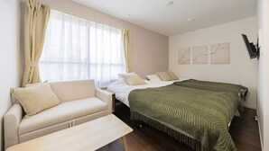 Ein Schlafzimmer mit einem Bett, einer Couch, einem Tisch und einem Fenster mit Vorhängen.