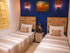 Un dormitorio con dos camas, una mesita de noche y apliques decorativos en la pared.