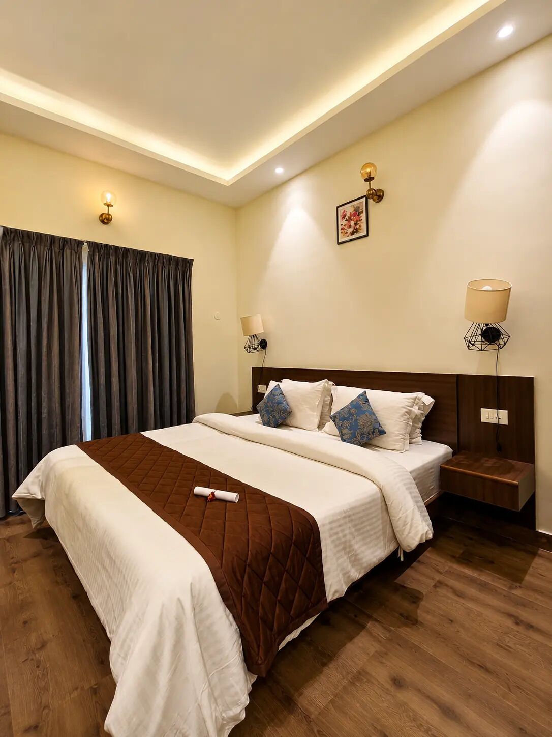 A hotel room with a large bed, two bedside tables, a wall-mounted lamp, and a ceiling light.