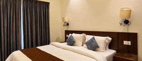 A hotel room with a large bed, two bedside tables, a wall-mounted lamp, and a ceiling light.