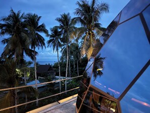A modern building with a glass facade reflecting palm trees and a clear sky. - Karuna Siargao Glamping (San Isidro)