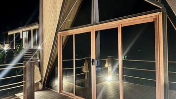 Un bâtiment moderne doté d’une terrasse en bois, de grandes fenêtres en verre et d’un escalier menant à un niveau supérieur.