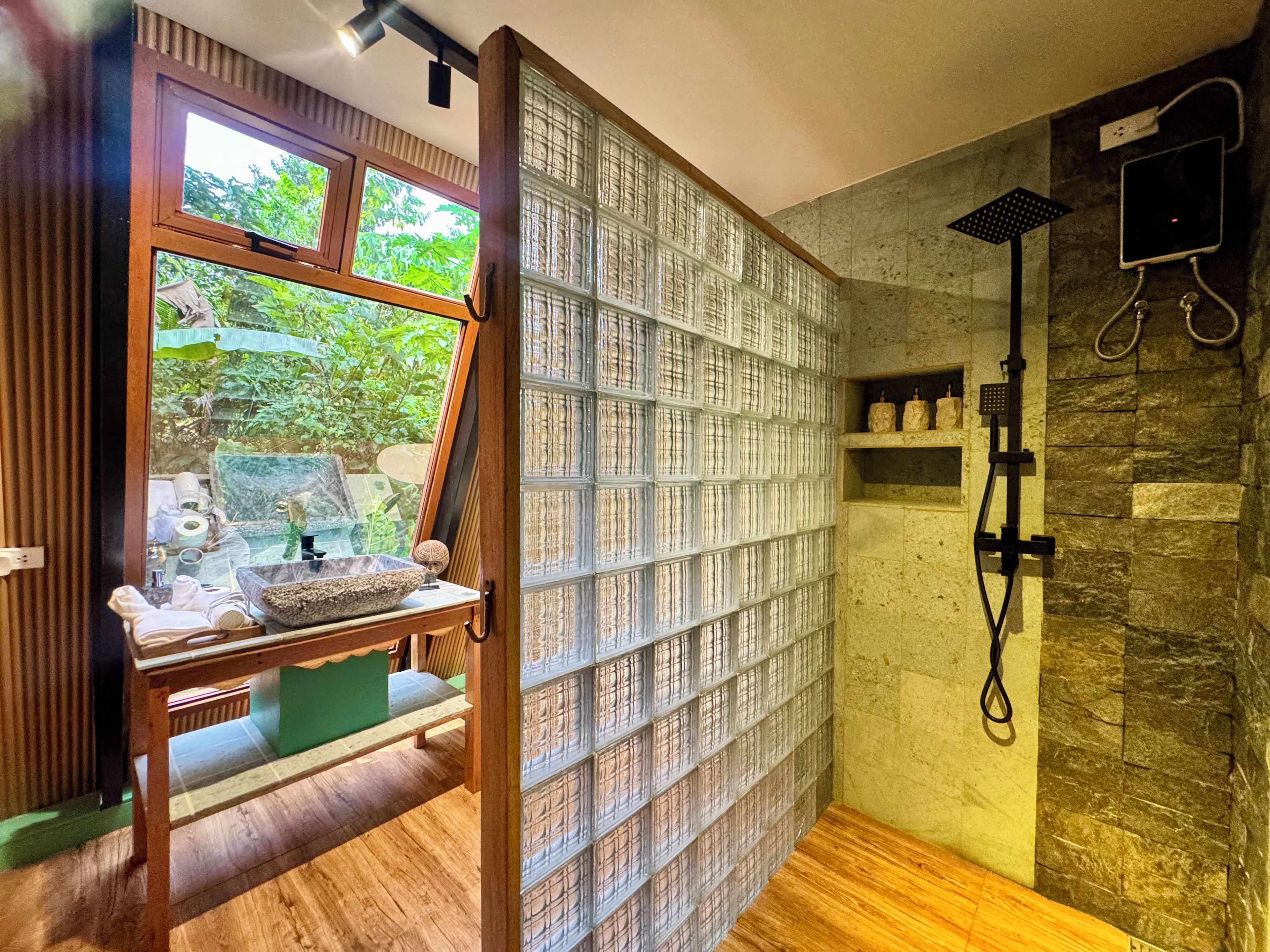 Une salle de bain avec une douche, un banc en bois et une fenêtre donnant sur un paysage verdoyant.