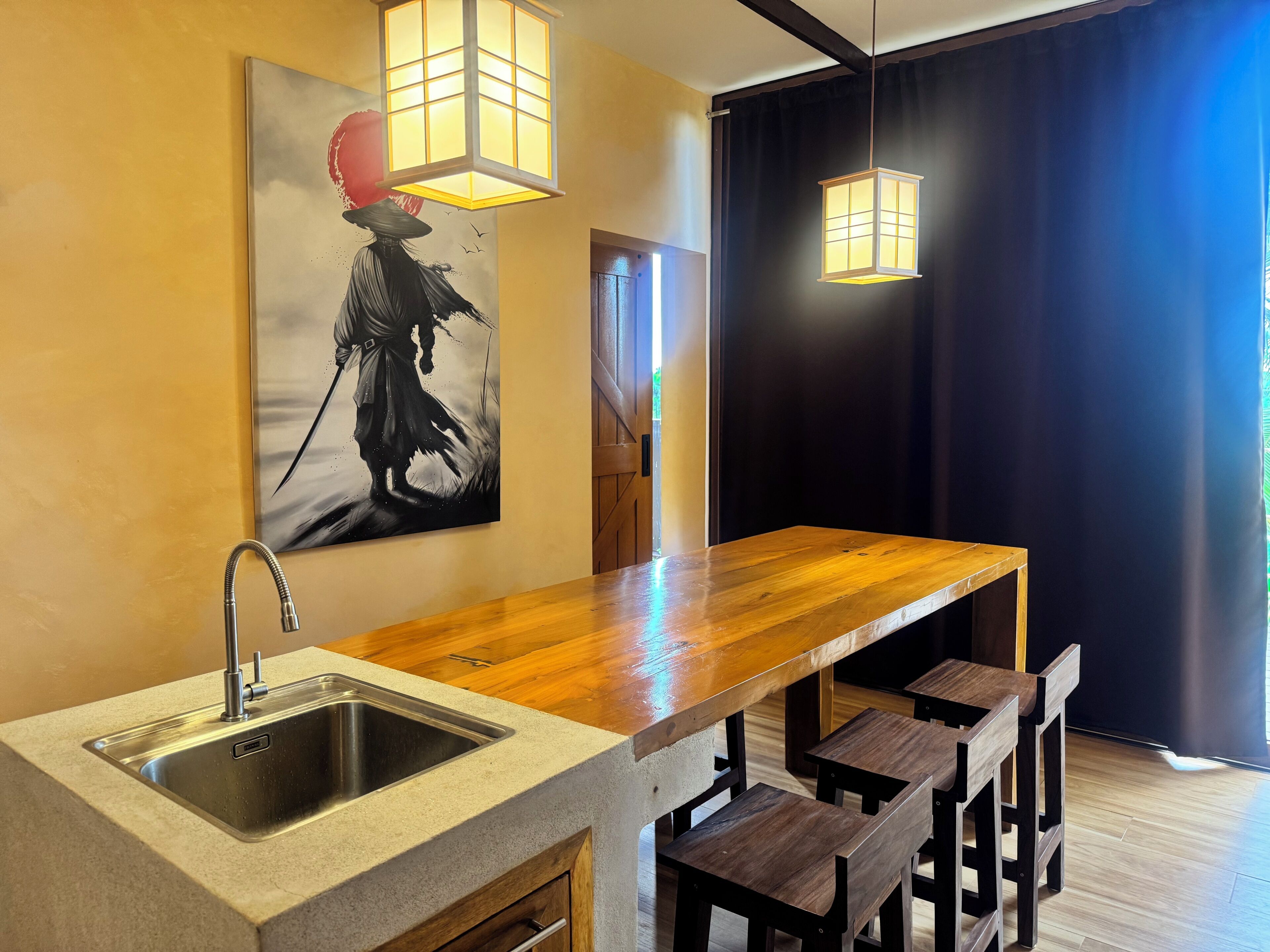 A modern kitchen with a wooden countertop, a stainless steel sink, and a black and white artwork on the wall.