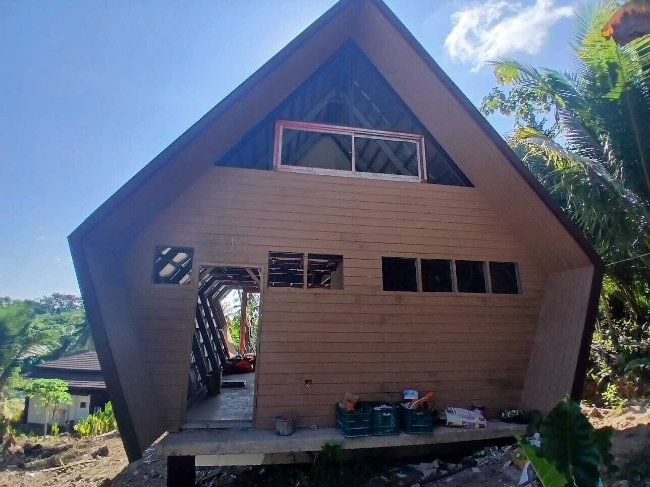 Una estructura de madera de dos pisos con techo inclinado, un acceso central y un pequeño porche.