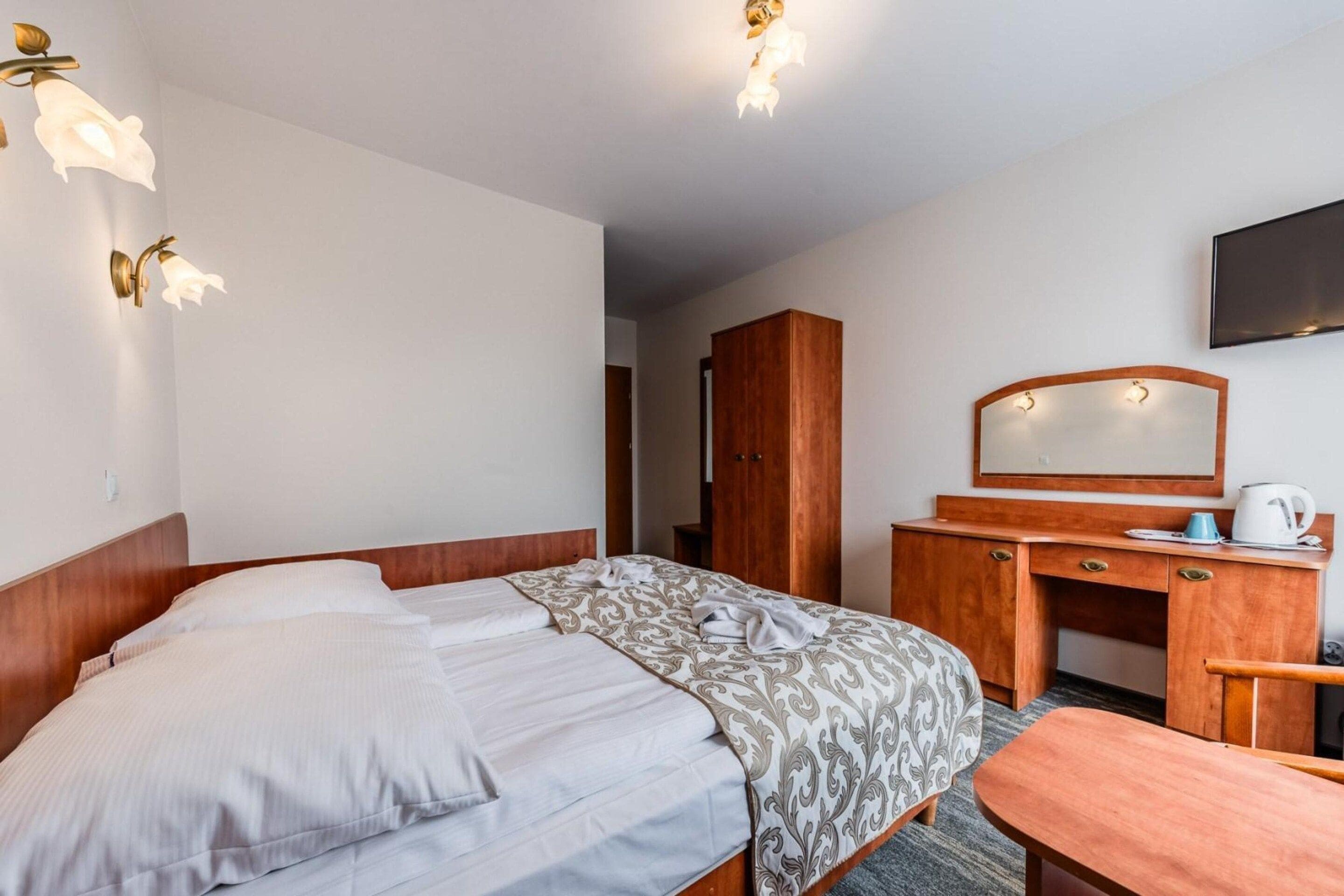 Une chambre d’hôtel équipée d’un lit, d’un bureau, d’une armoire et d’un téléviseur.