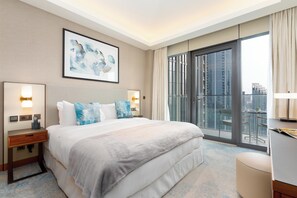 A hotel room with a large bed, two bedside tables with lamps, a painting on the wall, and a view of the city through a balcony. - bnbme - Address Opera T 1 - BR (Dubai)