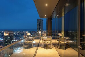 A high-rise balcony with a city view, furnished with tables and chairs, and a glass railing. - bnbme - Address Opera T 1 - BR (Dubai)