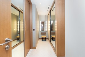 A hallway with mirrored walls, a bench, and a vanity with a mirror. - bnbme - Address Opera T 1 - BR (Dubai)