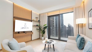 A modern living room with a flat-screen TV, a sofa, a coffee table, and a large window with curtains.