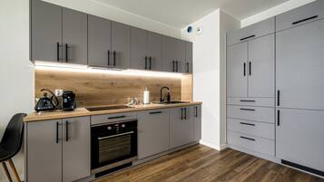 A modern kitchen with grey cabinets, a wooden countertop, a built-in oven, and a sink.